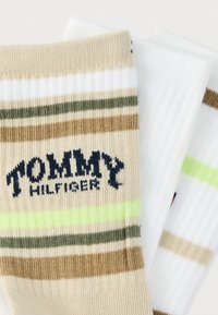 Τρία ζεύγη κάλτσες Tommy Hilfiger με ρίγες σε μπεζ, άσπρο, πράσινο και καφέ. Ένα ζευγάρι περιλαμβάνει το λογότυπο σε ναυτικό μπλε.