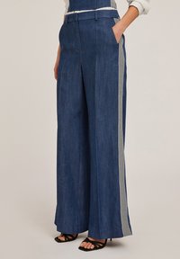 Wide-leg farkut tummansinistä sävyä ja pystysuoraa raitakuviota sivuilla. Varustettu etutaskuilla ja sileällä pinnalla.