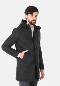 Cappotto isolato nero con cappuccio, chiusura con zip, bottoni a pressione, due tasche frontali e polsini elasticizzati. Texture liscia, design fino al ginocchio.