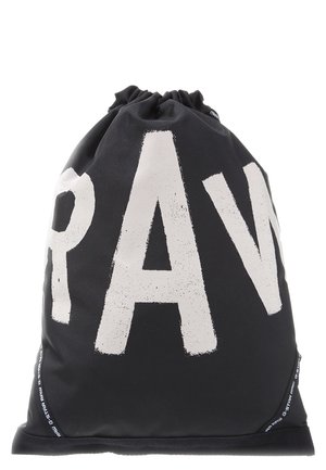 Schwarzer Beutel mit Kordelzug und großen, weißen, abgenutzten Buchstaben, die "RAW" buchstabieren, sowie gebrandete Borten entlang der unteren Kanten.