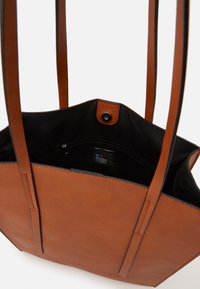 Sac fourre-tout en simili cuir marron avec deux longues anses, intérieur noir doublé, fermeture à pression et poche zippée à l'intérieur.