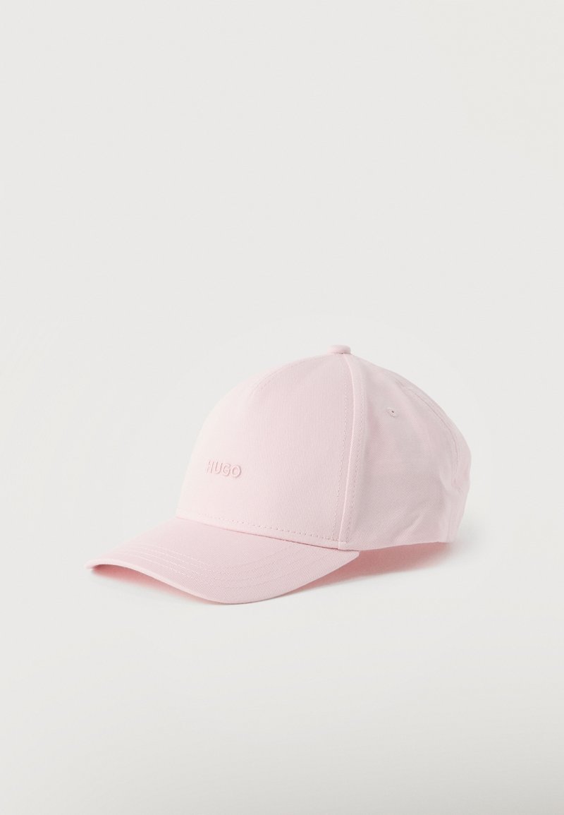 Ροζ ανοιχτό ροζ μπέιζμπολ καπέλο με κυρτή γείσο και διακριτικό κεντημένο λογότυπο "HUGO" στην μπροστινή πλευρά, τοποθετημένο σε απλό λευκό φόντο.