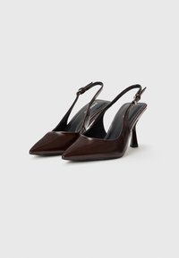 Ruske nahkaste slingback petke z ostrim nosom in tankim, sculptiranim peto. Opremljen z nastavljivim trakom okoli gležnja in gladko površino.