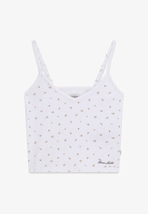 Witte cropped camisole met dunne verstelbare bandjes, kleine meerkleurige bloemenprint en "Guess Jeans" logo rechtsonder.