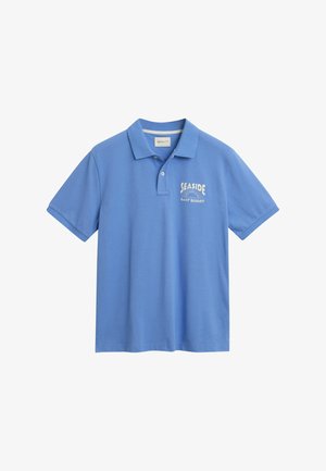 Polo shirt blu in cotone, con colletto e maniche corte. Sul davanti è presente un logo bianco con la scritta "SEASIDE" e "GANT RESORT."