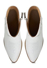 Botas de tobillo de cuero blanco con puntas afiladas, que presentan costuras decorativas y cremalleras laterales. Forro interior en tono marrón y tacón pequeño.