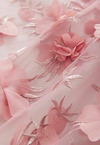 Ljusrosa nätmaterial med broderade blommotiv, med roséguld-accenter och detaljerade bladmönster. Mjuk och texturerad känsla.