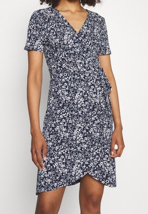 Marineblaues Kleid mit einem weißen Blumenmuster. Es verfügt über kurze Ärmel, einen V-Ausschnitt und ein Wickeldesign, das in der Taille gebunden wird. Glatte Stoffstruktur.
