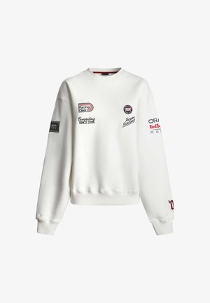 Biała bluza z okrągłym dekoltem z naszywkami i tekstem o tematyce wyścigowej, w tym „Racing Gear”, „Competing Since 2004” oraz „Oracle Red Bull Racing”.