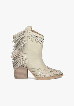 Stivaletto alla caviglia in pelle color crema con dettagli a frange, impreziosito da borchie argentate e accenti blu, caratterizzato da un tacco a blocco e punta appuntita.