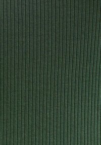 Donkergroen ribstof met verticale lijnen, met een zachte textuur en een lichte glans. Gelijkmatig geplaatste ribbels creëren een consistent patroon.