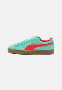 Baskets Puma en daim avec une tige turquoise, des accents rouges et une semelle en caoutchouc brun texturée. Fermeture à lacets standard et détail du logo.