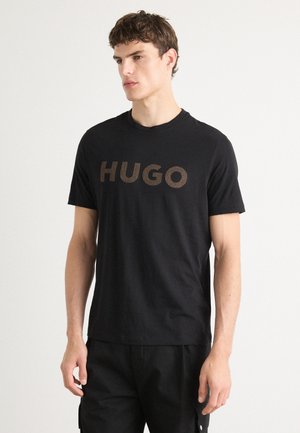 Sort bomulds T-shirt med en fed, tekstureret "HUGO"-logo i en kontrasterende finish, klassisk rund hals og korte ærmer.