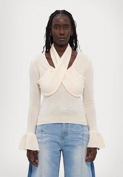 Maglione color crema con davanti drappeggiato, maniche lunghe con polsini svasati e orlo aderente, realizzato in un tessuto morbido e testurizzato.