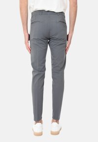 Chino grigi, affusolati, con tasche posteriori, design frontale piatto e una sottile texture, abbinati a sneakers bianche e una semplice t-shirt.