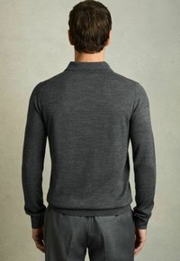 Pulover polo lung cu mâneci lungi de culoare gri închis, cu o textură moale și manșete în dantelă, purtat împreună cu pantaloni gri, croiți. Design simplu, clasic.