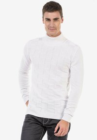 Pull en tricot blanc avec un col montant et un motif carré texturé. Manches longues et bords côtelés complètent le design.