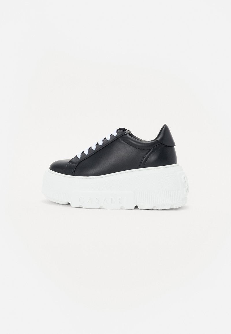 Black leather sneaker with white platform sole, textured detailing, and lace-up closure. Features a rounded toe and a sleek design.