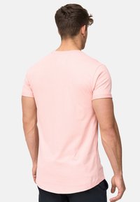 Helles rosa T-Shirt mit kurzen Ärmeln, aus Baumwolle gefertigt, mit rundem Ausschnitt und geradem Saum, mit minimalen Nähten auf der Rückseite.