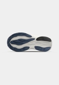 Semelle de chaussure avec un schéma de couleurs blanc et marine, présentant des rainures texturées, des motifs circulaires et un accent noir au niveau du talon.