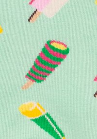 Sucette glacée rayée rose et verte sur un bâtonnet, posée sur un tissu vert menthe, avec d'autres illustrations colorées de sucettes glacées en arrière-plan.