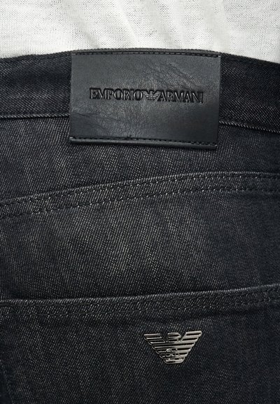 Μαύρο τζιν denim με ραμμένη δερμάτινη ετικέτα με το λογότυπο Emporio Armani στη μέση και μεταλλικό έμβλημα αετού στην πίσω τσέπη.