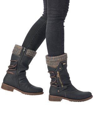 Schwarze, kniehohe Lederstiefel mit einem gestrickten Bündchen, seitlichen Reißverschlüssen, dekorativen Schnürsenkeln und einem strukturierten, holzähnlichen Absatz.