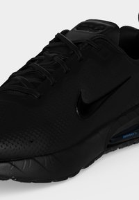 Chaussure de course Nike Air Max noire avec empeigne texturée, fermeture à lacets et amorti à air visible dans la semelle.