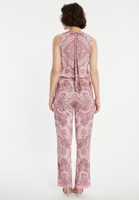 Roze paisley jumpsuit met een strikdetail op de rug, met een mouwloze top en rechte pijpen, afgewerkt met een egale roze zoom bij de enkels.