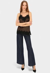 Brązowa satynowa koszulka na ramiączkach z czarną koronkową lamówką, zestawiona z szerokimi spodniami dżinsowymi o ciemnym odcieniu i czarnymi szpilkami z zaostrzonym noskiem. Proste ramiączka i elegancka faktura.