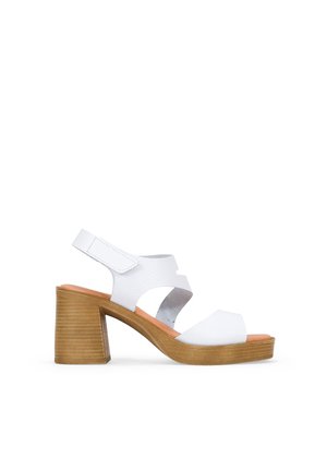 Sandalias de tacón blancas de piel con un diseño abierto, que cuentan con tiras entrelazadas y un tacón bloque sólido y texturizado de color marrón claro.