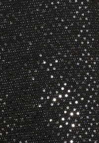 Černá látka s texturovaným vzorem, na které jsou uspořádány malé lesklé flitry ve formě mřížky, čímž vytváří odrazovou plochu.