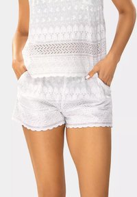 Białe szorty bawełniane z ozdobnym koronkowym wzorem, falbaniastym wykończeniem i bocznymi kieszeniami dla funkcjonalności i dodatkowego Detalu.