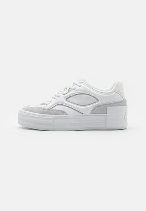 Sneakers bianchi e grigi con una tomaia in pelle liscia, dettagli in suede e suola in gomma testurizzata, caratterizzati da un design retrò e dettagli perforati.