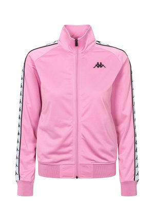 Chaqueta deportiva rosa con cremallera y cuello alto, logo negro en el pecho izquierdo y franjas blancas con logos negros a lo largo de las mangas.