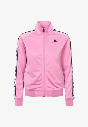 Chaqueta deportiva rosa con cremallera y cuello alto, logo negro en el pecho izquierdo y franjas blancas con logos negros a lo largo de las mangas.