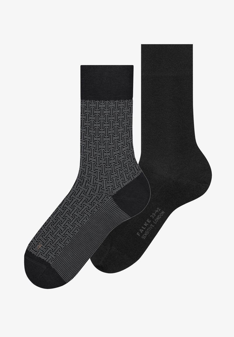 Deux chaussettes noires, l'une avec un motif géométrique gris entrelacé et un talon et une pointe noirs, l'autre entièrement noire avec la taille indiquée sur la semelle.
