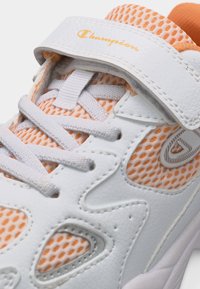 Baskets Champion blanches et orange avec tissu en mesh, fermeture à lacets et bride à scratch de marque sur le dessus.