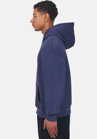 Navy blue hoodie with a drawstring hood, kangaroo pocket, ribbed cuffs, and hem, made of soft fabric with a smooth texture.