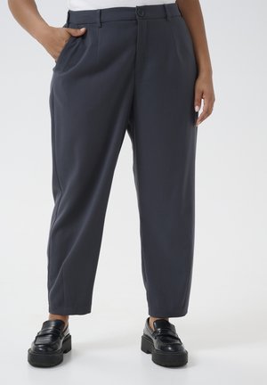 Dark gray tailored trousers with a straight leg, flat front, side pockets, and a button closure. Worn with black chunky shoes.