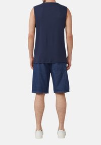 Navy mouwloos shirt met een ronde hals, gecombineerd met donkerblauwe denim shorts en witte sneakers, gezien vanuit de rug.