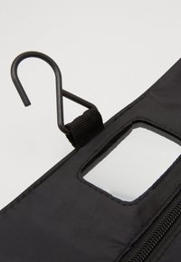 Borsa di stoffa nera con una finestra trasparente e un gancio in metallo. Presenta una cerniera, tessuto strutturato e cuciture lungo i bordi.