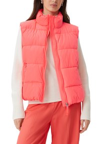 Rosa Steppweste mit hochschließendem Kragen, Reißverschluss und gestepptem Design. Getragen über einem weißen Pullover, kombiniert mit passenden rosa Hosen.