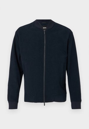 Navy bomber jacket with a zip front, ribbed cuffs, and collar. Made of textured fabric, featuring side pockets and a minimal design.