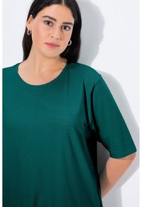 T-shirt verde a maniche corte con scollatura rotonda, realizzata in tessuto morbido, con un fit rilassato e una texture liscia.
