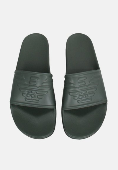 Le ciabatte in gomma nera presentano una fascia ampia con logo impresso, suole piatte e una soletta testurizzata per una maggiore aderenza.