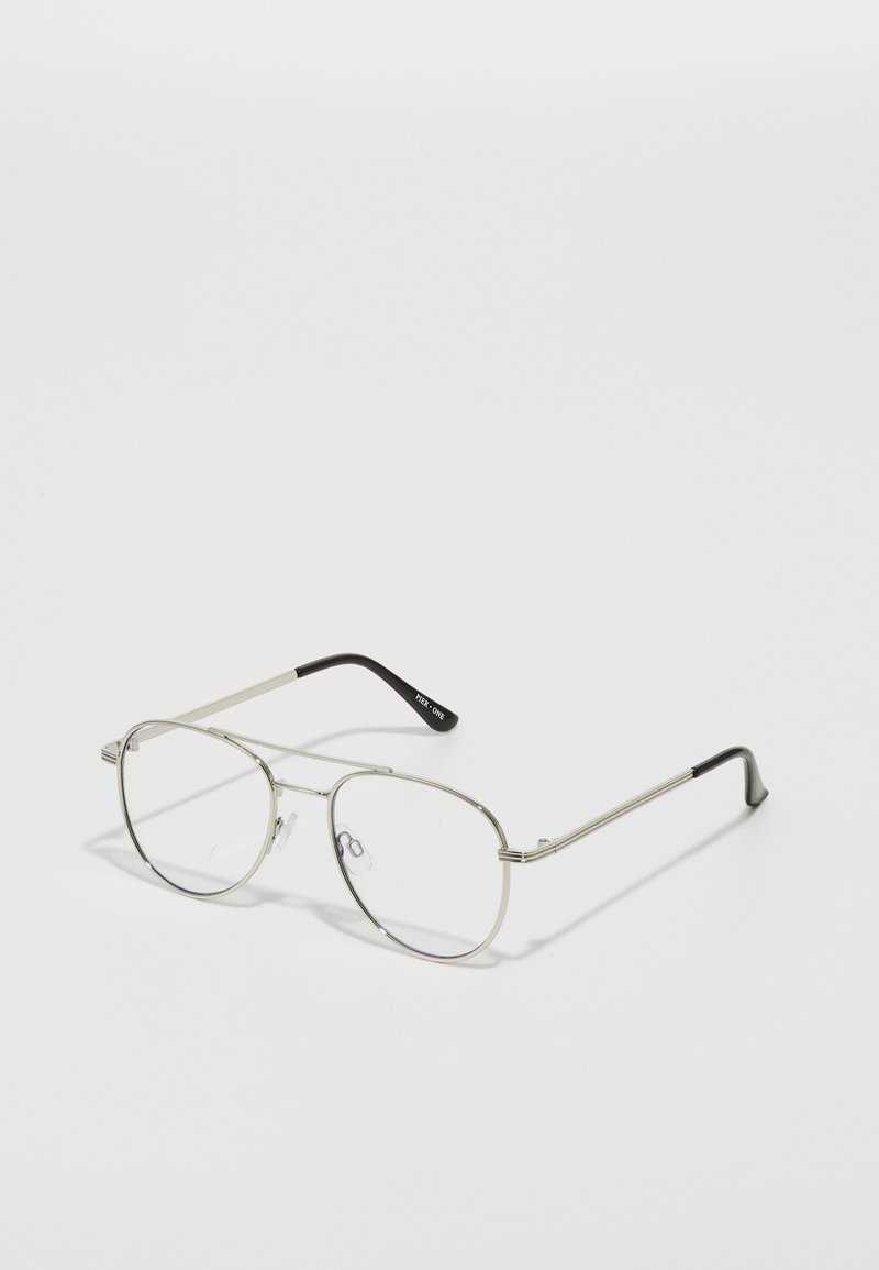 Lunettes en métal de forme ovale, avec une fine monture en argent et des verres transparents. Les branches noires se prolongent à partir des bras en métal.