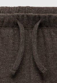 Bruine gestreepte stoffen tailleband met een trekkoord met textuuraccenten. Het materiaal lijkt zacht en flexibel, geschikt voor comfortabel dragen.