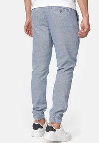 Helle blaue Jogginghose aus weichem Stoff, mit einem elastischen Bund und Bündchen, zwei seitlichen Taschen und einer Gesäßtasche.