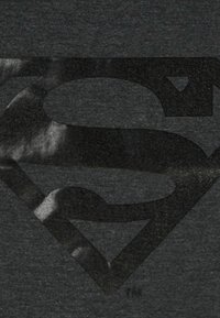 Czarny t-shirt w ciemnoszarym kolorze z dużym, błyszczącym czarnym logo Supermana umieszczonym na środku przodu, wykonany z miękkiej bawełny.